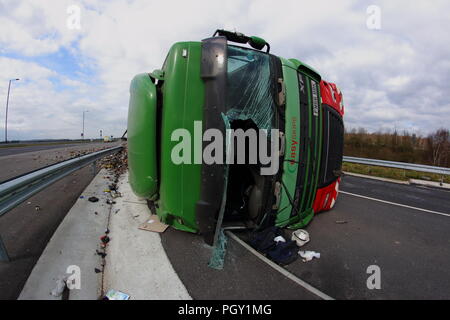 Ein Lkw umkippt und Leckagen ist es Laden der Verwertung von Abfällen über die neue Fahrbahn der Großen Yorkshire in Doncaster, South Yorkshire Stockfoto