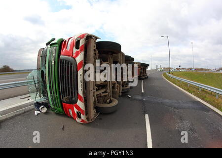 Ein Lkw umkippt und Leckagen ist es Laden der Verwertung von Abfällen über die neue Fahrbahn der Großen Yorkshire in Doncaster, South Yorkshire Stockfoto