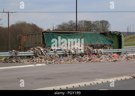 Ein Lkw umkippt und Leckagen ist es Laden der Verwertung von Abfällen über die neue Fahrbahn der Großen Yorkshire in Doncaster, South Yorkshire Stockfoto