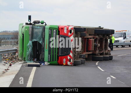 Ein Lkw umkippt und Leckagen ist es Laden der Verwertung von Abfällen über die neue Fahrbahn der Großen Yorkshire in Doncaster, South Yorkshire Stockfoto