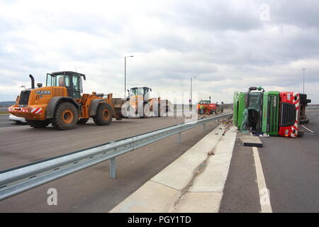 Ein Lkw umkippt und Leckagen ist es Laden der Verwertung von Abfällen über die neue Fahrbahn der Großen Yorkshire in Doncaster, South Yorkshire Stockfoto