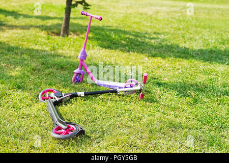 Zwei pink Scooter Für Mädchen auf grünem Gras. Stockfoto