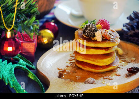 Pfannkuchen mit Beeren und Mutter mit Hintergrund Geschenk und Pine Cone unter Weihnachtsbaum, Holiday Party Dessert. Stockfoto