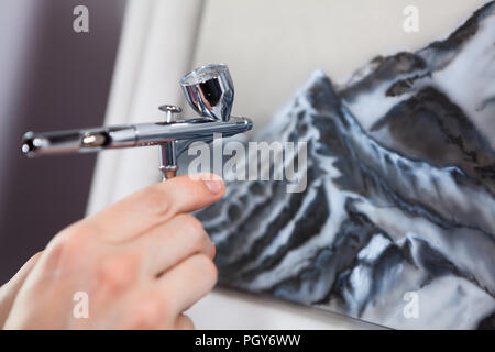 Stahl verchromt Airbrush gerät in der menschlichen Hand, Malen mit aerograph, Ansicht schließen Stockfoto
