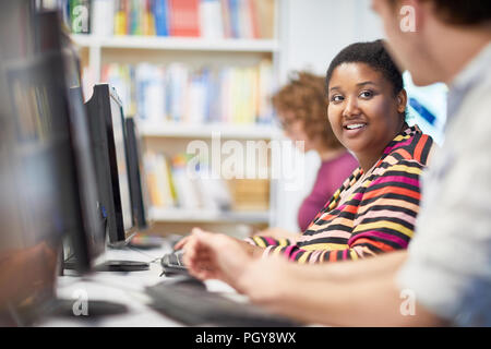 Lächelnd afrikanische Studentin die Teilnahme an Schulung in einem Computer im Klassenzimmer gemeinsam mit ihren Klassenkameraden Stockfoto