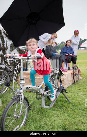 Newport, Wales - 23 Aug 14: Junge Mädchen Pedale Fahrrad Generator einschalten das Pedal powered Friseur am 14. August 2015 Im Green Gathering Festival Stockfoto