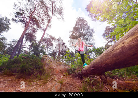 Lachende Mädchen gehen auf die große lange im Wald anmelden Stockfoto