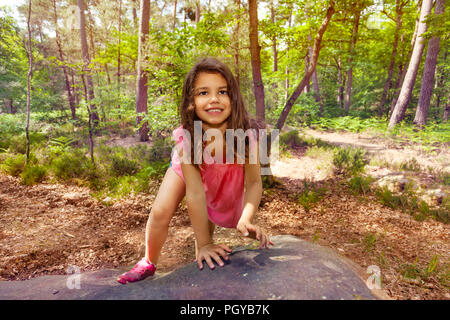 Porträt von einem kleinen Mädchen klettern auf einem Felsen im Wald im Sommer Aktivität mit Lächeln, Ansicht von oben Stockfoto