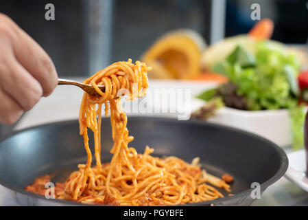 Spaghetti aufgehoben durch Gabelstapler mit Gemüse und Salat Teller Hintergrund. Essen und Cousine Konzept. Italienisches Essen in der Küche Thema. Rezept und Menü Thema. Stockfoto