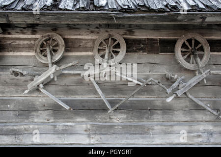 Vintage traditionelle Alte hölzerne durchdrehende Räder auf der hölzernen Wand der Ställe. Stockfoto