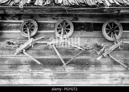 Vintage traditionelle Alte hölzerne durchdrehende Räder auf der hölzernen Wand der Ställe. Stockfoto