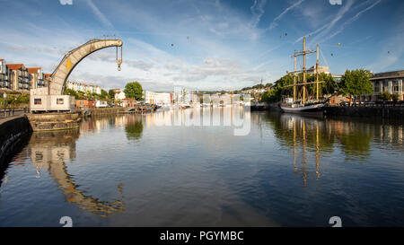 Bristol, England, Großbritannien - 11 August 2018: Heißluftballone Fliegen über einem traditionellen Dampf Kran und Tall Ship in Bristol Schwimmenden Hafen in der Dämmerung durin Stockfoto