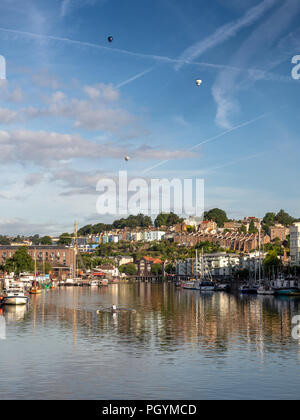 Bristol, England, Großbritannien - 11 August 2018: Ein einsamer Ruderer Züge auf Schwimmenden Hafen von Bristol, unter einem Trio von Heißluftballons in Bristol Balloon Stockfoto