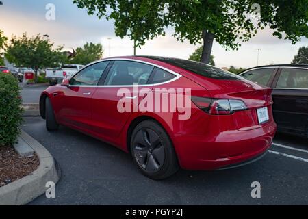 Seitenansicht eines roten Tesla Modell 3 Elektroauto von Tesla Motors unter einem dramatischen Himmel in der San Francisco Bay Area, Dublin, Kalifornien, 21. Mai 2018. () Stockfoto