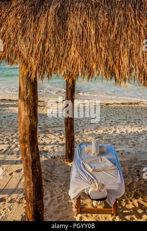 Eine massage Tabelle unter dem Strohdach auf einem tropischen Strand Stockfoto