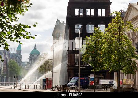 Belfast, UK. 29. August 2018. Mitglieder der Nordirischen Fire and Rescue Service (NIFRS) weiter unten die ausgebrannte Hülle des Primark Store im Zentrum von Belfast zu feucht. Die historische wurde komplett zerstört nach Feuer es Credit: Bonzo/Alamy Leben Nachrichten verschlungen Stockfoto