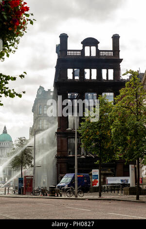 Belfast, UK. 29. August 2018. Mitglieder der Nordirischen Fire and Rescue Service (NIFRS) weiter unten die ausgebrannte Hülle des Primark Store im Zentrum von Belfast zu feucht. Die historische wurde komplett zerstört nach Feuer es Credit: Bonzo/Alamy Leben Nachrichten verschlungen Stockfoto