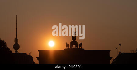 Berlin, Deutschland. 29 Aug, 2018. Das Brandenburger Tor und den Fernsehturm kann nur als Silhouette gegen die aufsteigende Sonne gesehen werden. Credit: Paul Zinken/dpa/Alamy leben Nachrichten Stockfoto