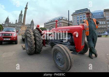 Glasgow, Schottland, Großbritannien. 29 August, 2018. Mittags Besucher, wo man ein bisschen lebendiger Geschichte als Classic Red 1964 Massey Ferguson 35 X Traktor behandelt erschien in der Stadt George Square. Einheimische und Touristen beobachtet, wie der Rasen, die für die jüngsten europäischen Meisterschaften einladenden Zentrum aufgehoben wurde ersetzt wurde. Das Modell Sport ungewöhnliche Doppel Räder die Traktion zu erhöhen und wurde von der stolze Besitzer dargestellt geändert. Gerard Fähre / alamy Nachrichten Stockfoto