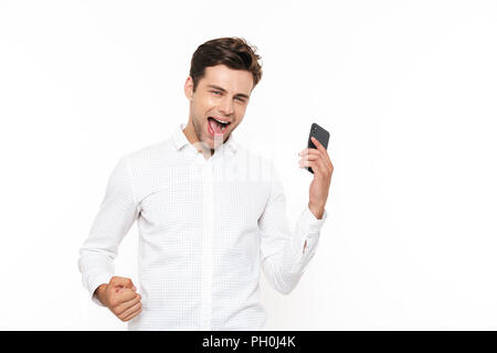 Happy europäischen Mann mit kurzen dunklen Haaren zu schreien, während sie Smartphone auf weißem Hintergrund Stockfoto
