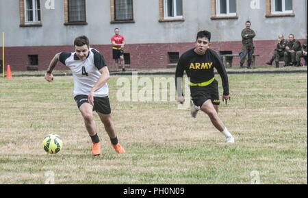 Ein 23 Artillery Brigade, polnisches Land Forces Soldat läuft nach einem Fußball bei einem Match gegen den US-Soldaten in die 91St Ingenieur Bataillon zugeordnet, 1. gepanzerte Brigade Combat Team, 1 Calvary Division und Firma B, 151 Expeditionary Signal Battalion, South Carolina National Guard, während ein Fußball-Spiel zum Gedenken an den im Armee Geburtstagsfeier im polnischen Land Forces Base in Boleslawiec, Polen, 14. Juni 2018 statt. Die gemeinsame Feier inklusive einer Basis-weit laufen, Veranstaltungen und einen Kuchen Cutting. Stockfoto