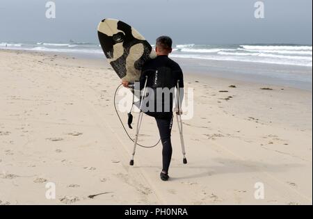 DEL MAR, Kalifornien (14. Juni 2018) Marine Corps Veteran Chris kleine Spaziergänge an den Ufern der Stadt Strand und macht sich bereit zum Surfen zusammen mit anderen Patienten aus Naval Medical Center San Diego (NMCSD) Surf Klinik. Der Tag markiert auch 10. Jahrestag NMCSD's Surf Klinik Feier, und Kleine hat einen Patienten mit dem Surf Klinik für 10 Jahre gewesen. Die Klinik wird von der Gesundheit und der Wellness Abteilung koordinierte Verwundeten, Kranken und Verletzten service Mitglieder durch Übung und entspannende Therapie zu rehabilitieren, ihre Funktion und Mobilität zu verbessern. Stockfoto