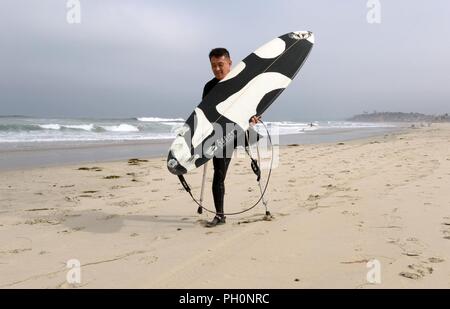 DEL MAR, Kalifornien (14. Juni 2018) Marine Corps Veteran Chris kleine Spaziergänge an den Ufern der Stadt Strand und macht sich bereit zum Surfen zusammen mit anderen Patienten aus Naval Medical Center San Diego (NMCSD) Surf Klinik. Der Tag markiert auch 10. Jahrestag NMCSD's Surf Klinik Feier, und Kleine hat einen Patienten mit dem Surf Klinik für 10 Jahre gewesen. Die Klinik wird von der Gesundheit und der Wellness Abteilung koordiniert, Verwundete, Kranke zu rehabilitieren, und verletzten Service Mitglieder durch Übung und entspannende Therapie, um ihre Funktion und Mobilität und psychische Wohlbefinden zu verbessern. Stockfoto