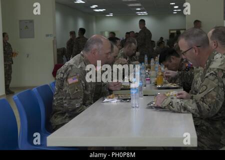 U.S. Army National Guard Brig. Gen. Joseph Streff, Alaska ARNG Commander, setzt sich für das Mittagessen mit seiner Alaska Wachposten und internationalen Partnern in der khaan Quest 18 Kommandostellenübung, fünf Hügeln, Mongolei, 16. Juni 2018 teilnehmen. Khaan Quest 18 ist eine regelmäßige, multinationale Übung von der US Pacific Command gefördert und bewirtet jährlichen von der mongolischen Streitkräfte. KQ18 ist der neueste in der laufenden Serie von Übungen, die entworfen sind, um den Frieden und die Sicherheit in der Region zu fördern. Die diesjährige Übung markiert den 16. Jahrestag der Schulungsveranstaltung. Stockfoto