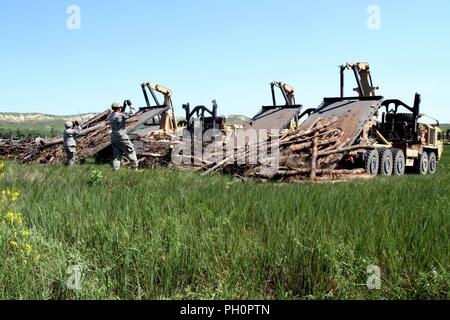 Us-Armee SPC. Tyler Wassenburg und Sgt. Marla Manarang, LKW-Fahrer mit der 137 Transport Unternehmen, Kansas Army National Guard, guide Fahrzeuge bei Red Shirt, S.D., 15. Juni 2018. Die Soldaten Holz zur Unterstützung der Holz schleppen entlastet, als Teil des Goldenen Coyote Übung. Stockfoto