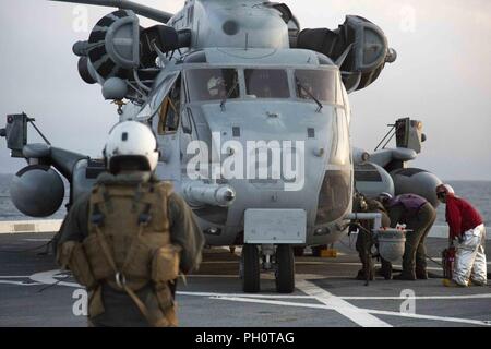 Ein US-Marine Crew Chief mit dem 22 Marine Expeditionary Unit wartet, während ein CH-53E Super Stallion "Heavy lift Helicopter, die durch die U.S. Navy Flight Crew an Bord der USS Arlington (LPD-24) während der Amphibischen Squadron (PHIBRON) - MEU Integration Training in den Atlantik, 15. Juni 2018 betankt wird. PHIBRON-MEU Integration ist eine zweiwöchige Schulung Entwicklung, die Matrosen und US-Marines als zusammengehörige Einheit in der Vorbereitung für die bevorstehende Bereitstellung zu trainieren. Stockfoto