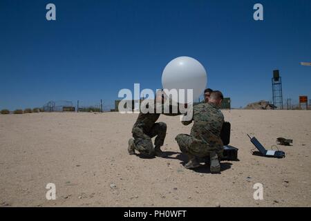 Meteorologie und Ozeanographie Analyst forecast Marines mit Distanz ein, Marine Air Control Squadron 24, Marine Air Control Gruppe 48, 4 Marine Flugzeugflügel, bereiten ein wetterballon von der taktischen Atmospheric Sounding Kit zu lösen, während integrierte Ausbildung Übung 4-18 bei Marine Corps Air Ground Combat Center Twentynine Palms, Calif., 21. Juni 2018. METOC Marines mit Marine Air Ground Task Force 23 96 Stunden Wettervorhersagen und die vorhergesagten Auswirkungen auf Ausbildung, Truppe oder Flugbewegungen, oder die Benutzung von nachtsichtbrillen. Stockfoto