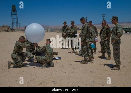 Meteorologie und Ozeanographie Analyst forecast Marines mit Distanz ein, Marine Air Control Squadron 24, Marine Air Control Gruppe 48, 4 Marine Flugzeugflügel, bereiten ein wetterballon von der taktischen Atmospheric Sounding Kit zu lösen, während integrierte Ausbildung Übung 4-18 bei Marine Corps Air Ground Combat Center Twentynine Palms, Calif., 21. Juni 2018. METOC Marines mit Marine Air Ground Task Force 23 96 Stunden Wettervorhersagen und die vorhergesagten Auswirkungen auf Ausbildung, Truppe oder Flugbewegungen, oder die Benutzung von nachtsichtbrillen. Stockfoto