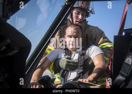 Senior Airman Justin Lang, hinten, 23d Bauingenieur Squadron (CES) Feuerwehrmann, gewinnt eine simulierte Opfer von einer HH-60G Pave Hawk bei einer Rettung Ausbildung Szenario, 19. Juni 2018, bei Moody Air Force Base, Ga 23d CES Feuerwehrmänner der Ausbildung ihre Kenntnisse und der Vorbereitung von, wie man richtig abschalten und Rescue Crew Mitglieder aus einer HH-60 zu bewerten. Stockfoto