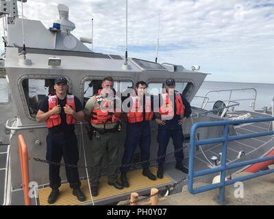 Die Besatzungsmitglieder von der Coast Guard Station Manistee, Michigan und ein Manistee County Sheriff's Deputy posieren für ein Foto an Bord eines 45-Fuß-antwort Boot, 23. Juni 2018, nach der Rettung von einem Mann, der in den Lake Michigan. Die multi-Agentur Crew haben gemeinsam die Unterkuehltes Mann aus dem Wasser zu erleichtern und ihn an Land Transport für medizinische Behandlung. Stockfoto