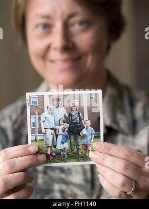 Airman 1st Class Crystal Jenkins, ein Fotojournalist, der 673 d Air Base Wing öffentlichen Einheit Angelegenheiten zugewiesen, hält ein Foto von ihr und ihrer Familie nachdem Sie von der Defense Information School in Fort Meade, Md., 2017. Jenkins war inspiriert der US Air Force während der 2016 Arctic Thunder Open House bei Joint Base Elmendorf-Richardson, Alaska zu verbinden. Nachdem die Anwerbung im Jahr 2016 war sie die Gelegenheit gegeben, zu der sie von eingezogen wurde, zurückzukehren. Stockfoto