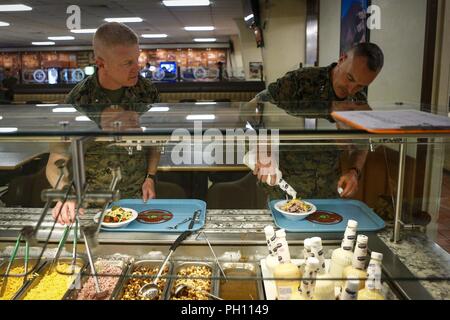 Us Marine Corps Generalmajor Vincent Coglianese (rechts), Commander, Marine Corps Installationen Befehl, Assistent des stellvertretenden Kommandanten, Anlagen und Logistik, und Brig. Gen. Paul Rock, Kommandierender General, Marine Corps Installationen Pacific, dienen sich Salat am Anderson Chow Halle während einer Tour von Marine Corps Base Hawaii, 25. Juni 2018. Generalmajor Coglianese führt eine Tour durch alle Unterseiten innerhalb der Marine Corps Installationen Pacific mehr Verständnis für die Probleme und Umstände, die jeder base Flächen zu entwickeln. Stockfoto