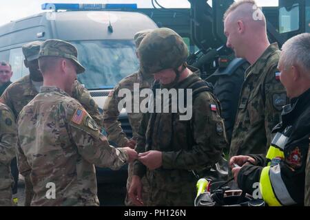 Armee 1. Lt Adam Eyerle, die loslösung Kommandant der 962Nd Ordnance Company, 143 Bekämpfung Sustainment Support Battalion, präsentiert eine Münze, ein polnischer Soldat aus dem 10 gepanzerte Kavallerie Brigade, nach einem Emergency Responder Ausbildung Übung in Swieteszow, Polen, 20. Juni 2018. Die 962Nd Ordnance, ein US Army Reserve von New York, ist zur Unterstützung der Atlantischen lösen in Europa eingesetzt. Stockfoto