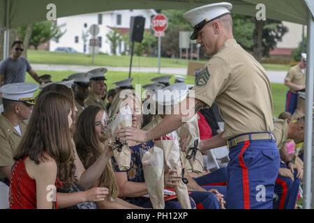 Staff Sgt. Jakob Hartwig, Officer Auswahlassistenten, Offizier Auswahl Team Iowa City, Geschenke Blumen an die Familie von Maj. Brian Blaine beim Marine Corps Recruiting Station von Des Moines Ändern des Befehls Zeremonie am Lager Ausweichen, Johnston, Iowa, 23. Juni 2018. Blaine aufgegeben das Kommando über die "Wolfpack Nation" Maj. Patrick J. Skehan. Stockfoto