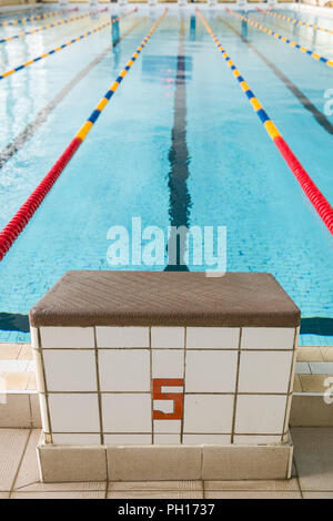 Startlöchern und Gassen in einen Pool. Flanke von innen Sport Pool. Plattformen, beginnend mit der Nummer 5 für Schwimmen rennen und Wettbewerb Stockfoto