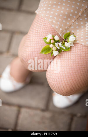 In der Nähe der Beine junge Frau mit Blumen des Schönen apple tree Festlegung auf Ihnen. Blumen auf Girl's Knie. Apple blühen in den Park. im Freien. Stockfoto