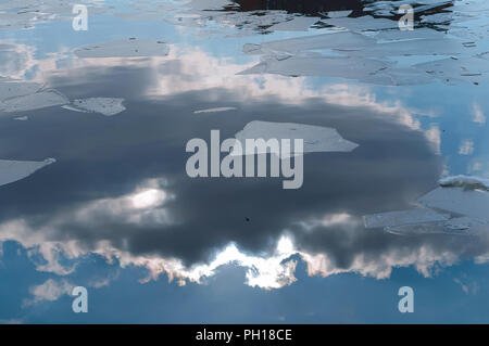 Stücke von Eis auf dem Wasser im frühen Frühjahr, Wolken im Wasser spiegelt Stockfoto