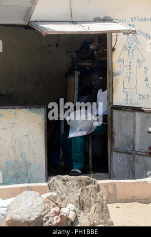 Weg zum Kalvarienberg, SENEGAL - 23.April 2017: Unbekannter senegalesischen Mann mit Kopfhörer sitzt in der Gebäude- und hält einige Gerät. Immer noch viele Menschen in Stockfoto