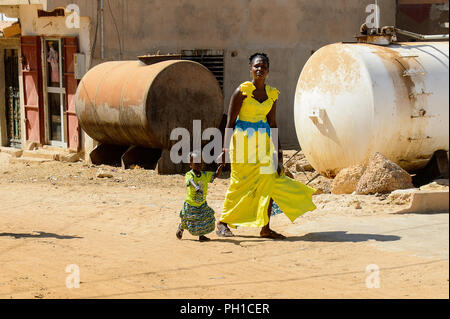 Weg zum Kalvarienberg, SENEGAL - 23.April 2017: Unbekannter senegalesische Frau im gelben Kleid geht mit einem kleinen Mädchen. Noch viele Menschen im Senegal leben in Stockfoto