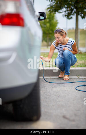 Junge Frau Kontrolle der Auto Luftdruck aufpumpen Es Stockfoto