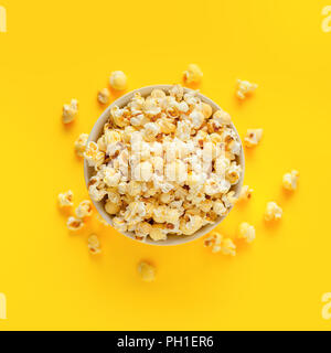 Popcorn im Plastiketui auf gelbem Hintergrund, Ansicht von oben Stockfoto