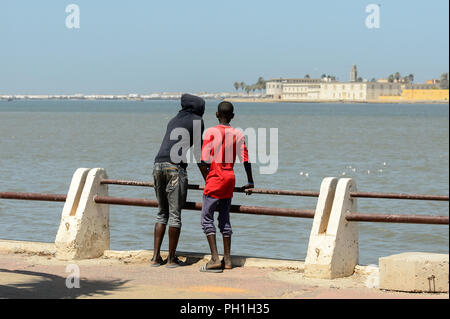 SAINT LOUIS, SENEGAL - Apr 25, 2017: Unbekannter senegalesischen zwei Jungen stehen auf dem Pier und den Blick auf den Ozean in Saint Louis, einer der größten Stadt Stockfoto