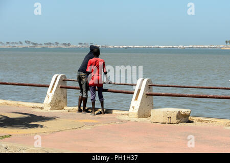 SAINT LOUIS, SENEGAL - Apr 25, 2017: Unbekannter senegalesischen zwei Jungen stehen auf dem Pier und den Blick auf den Ozean in Saint Louis, einer der größten Stadt Stockfoto