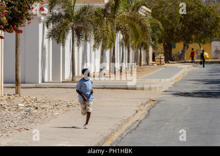 SAINT LOUIS, SENEGAL - Apr 24, 2017: Unbekannter senegalesischen kleiner Junge läuft entlang der Straße mit Palmen in Saint Louis, einer der größten Stadt Stockfoto