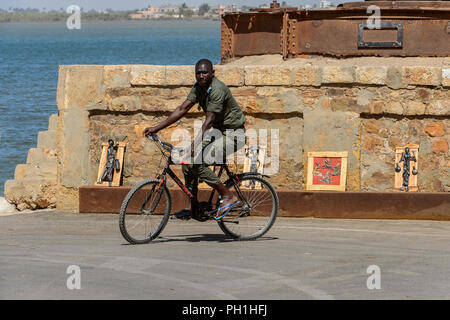 SAINT LOUIS, SENEGAL - Apr 24, 2017: Unbekannter senegalesischen Mann reitet ein Fahrrad in Saint Louis, eine der größten Städte in Senegal Stockfoto