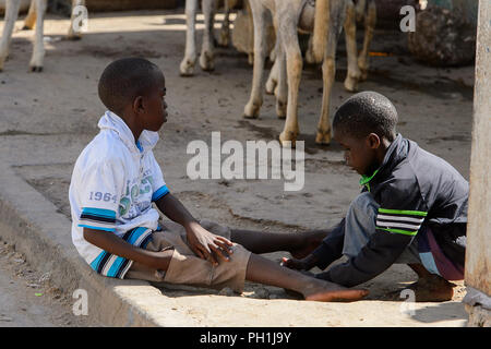 SAINT LOUIS, SENEGAL - Apr 24, 2017: Unbekannter senegalesischen zwei kleine Jungen auf dem Boden neben der Straße auf den lokalen Markt von Saint Louis, Se spielen Stockfoto